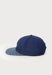 Marine baseball cap med skygge i blå tern. Blødt materiale, struktureret form, seks-panel design og dekorativ syning på fronten.
