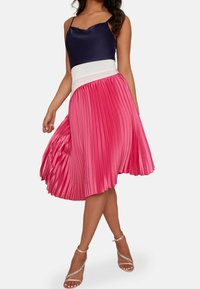 Ein plissierter rosa Rock mit einem weißen Bund, kombiniert mit einem dunkelblauen Satintop. Der Rock zeichnet sich durch ein fließendes Design und eine glänzende Textur aus.