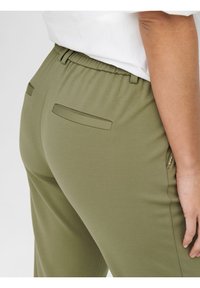 Olivově zelené kalhoty se strečovým pasem, dvěma zadními kapsami a hladkým povrchem. Obsahují detail s boční kapsou na zip.