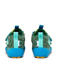 Scarpe in tessuto verde con suole blu, cinturini regolabili e dettagli gialli. Presentano un tessuto testurizzato e un dettaglio di design giocoso sul tallone.