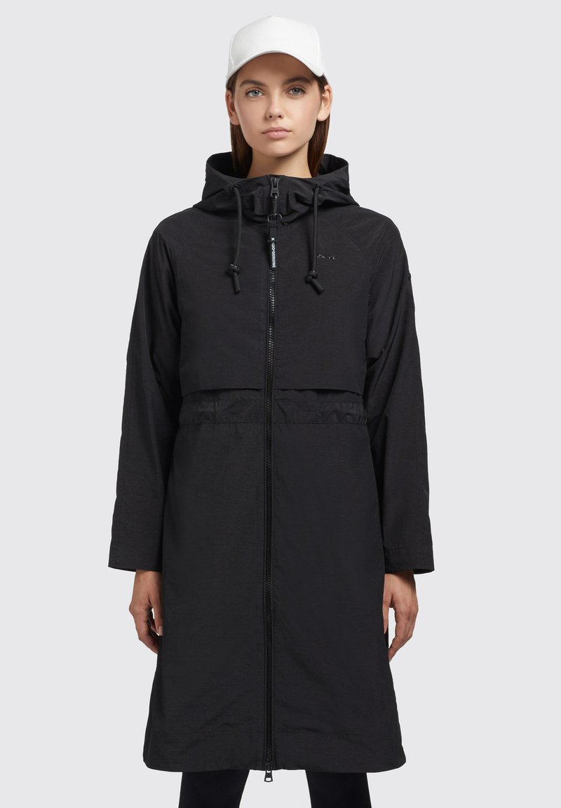 Manteau long noir imperméable avec fermeture éclair à l'avant, capuche réglable et cordons de serrage. Présente un design à couche supérieure cropped et des manches longues.