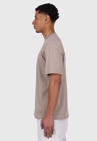 Short-sleeve, crew-neck t-shirt in light brown, made of cotton with a smooth texture. Features a relaxed fit and minimalistic design.