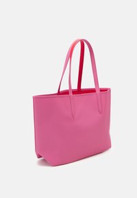 Sac fourre-tout rose avec une texture lisse, de forme rectangulaire haute, et deux poignées d'une nuance de rose légèrement plus foncée. Aucun élément métallique ni ornement visible.