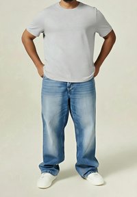  camiseta gris de cuello redondo, jeans de mezclilla azul claro de corte holgado, zapatillas blancas, tela suave, ajuste relajado, detalles mínimos.