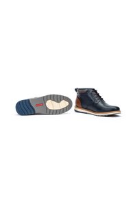 Navy leather ankle boots with brown accents, round toe, and lace-up design. Features a patterned, textured sole with two-tone color.