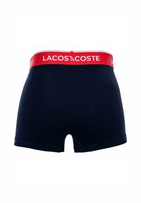 Boxer in cotone navy con cintura rossa che presenta il logo "LACOSTE", dal design aderente e dalla texture liscia.