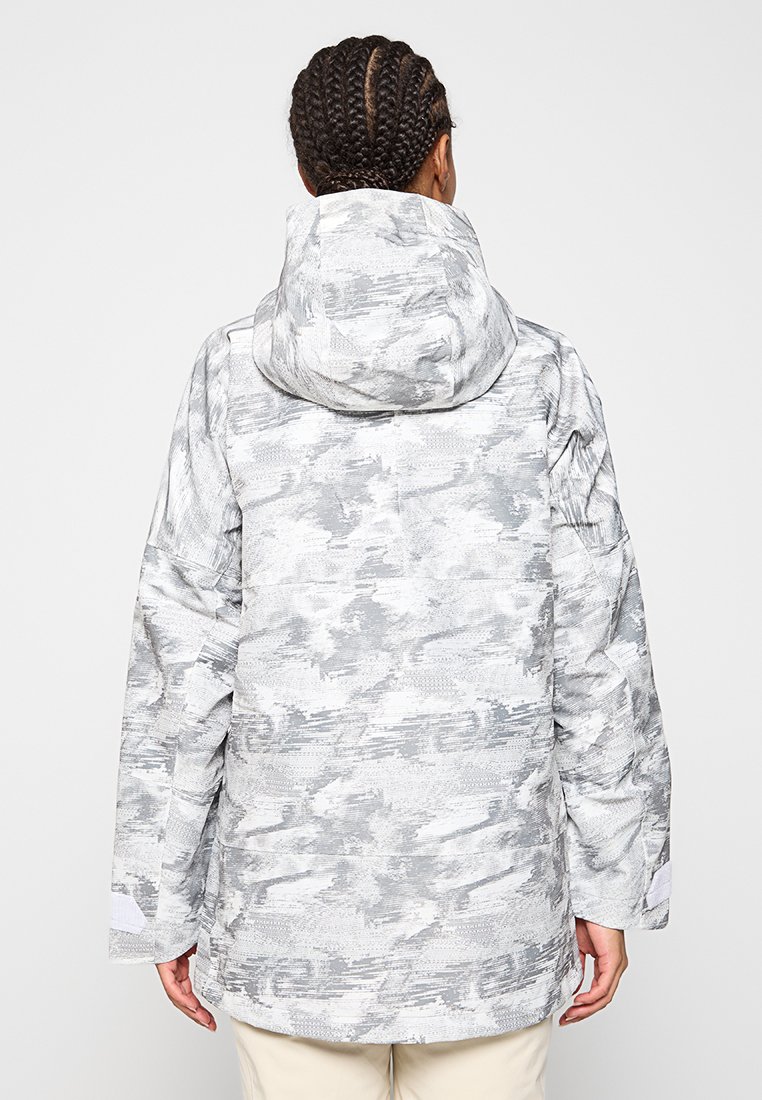 Chaqueta con capucha de diseño gris con patrón, de corte holgado, que presenta una tela texturizada y mangas amplias. El diseño incluye formas abstractas en diferentes tonalidades.