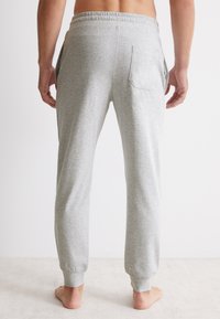 Grijze katoenen sweatpants met een elastische tailleband, zijzakken en een enkele achterzak, met een ontspannen pasvorm en boorden bij de enkels.