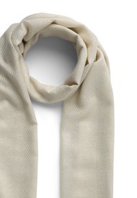 Sciarpa beige morbida con un sottile motivo a zigzag, drappeggiata con nonchalance su uno sfondo bianco.