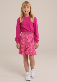 Růžová dlouhá rukávová košile s nápisem "UDĚLEJ DNES ŠÍLENOST", doplněná o růžovou sukni s volány, která má leopardí vzor a elastický pas.