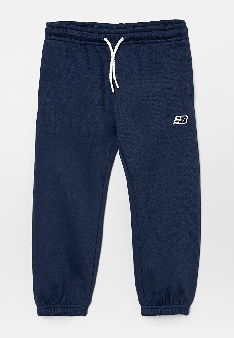 Pantalons de survêtement bleu marine avec des poignets et une taille élastiques, dotés d'un cordon de serrage blanc et d'un petit logo blanc sur la cuisse gauche.