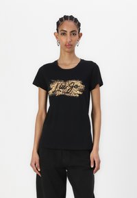 T-shirt nera in cotone con un logo in stampa animale dorata e un design testurizzato sul fronte. Maniche corte ecollo rotondo.