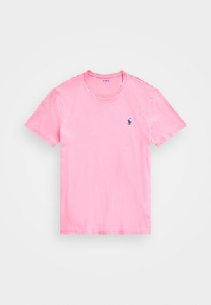 Pinkes T-Shirt mit kurzen Ärmeln und Rundhalsausschnitt, mit kleinem schwarzem, gesticktem Logo auf der linken Brust, vor einem schlichten weißen Hintergrund.
