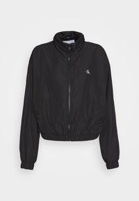 Černá bomber bunda vyrobená z lehkého materiálu, s vysokým límcem, elastickými manžetami a páskem v pase s malým logem.