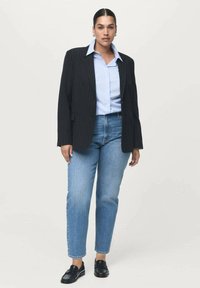 Črno prugasta blazer preko svetlo modre srajce z gumbi, v kombinaciji z svetlim pranjem ravnimi jeans hlačami in črnimi loafers. Preprosta, moderna obleka.