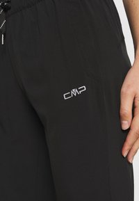 Pantalon de sport noir en tissu léger, doté d'une ceinture élastique, d'un cordon de serrage et d'un petit logo CMP argenté sur la cuisse.