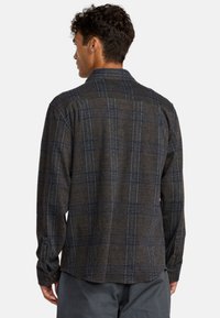 Geruite shirt in donkergrijs met blauwe accenten, voorzien van een standaardkraag, lange mouwen en knopenmanchetten. De achterkant toont de schouderpas en naaddetails.