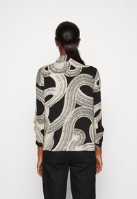 Mustat puserot, joissa on virtaava valkoinen abstrakti kuvio, pitkät hihat ja kaulus. Pehmeä kangas, jonka pinta on sileä.