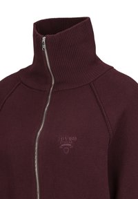 Bordeauxrode sweatshirt met ritssluiting, hoge geribbelde kraag en geborduurd logo. Voorzien van gladde stof en een zilveren rits aan de voorkant.