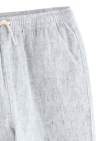 Un pantalon en lin gris doté d'une taille à cordon, d'une poche latérale et d'un tissu texturé et respirant, idéal pour un usage décontracté.