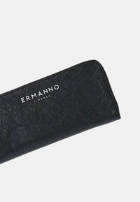 Portafoglio in pelle nera con finitura testurizzata, caratterizzato dal marchio argentato "ERMANNO FIRENZE" sul davanti e un design con chiusura a zip.