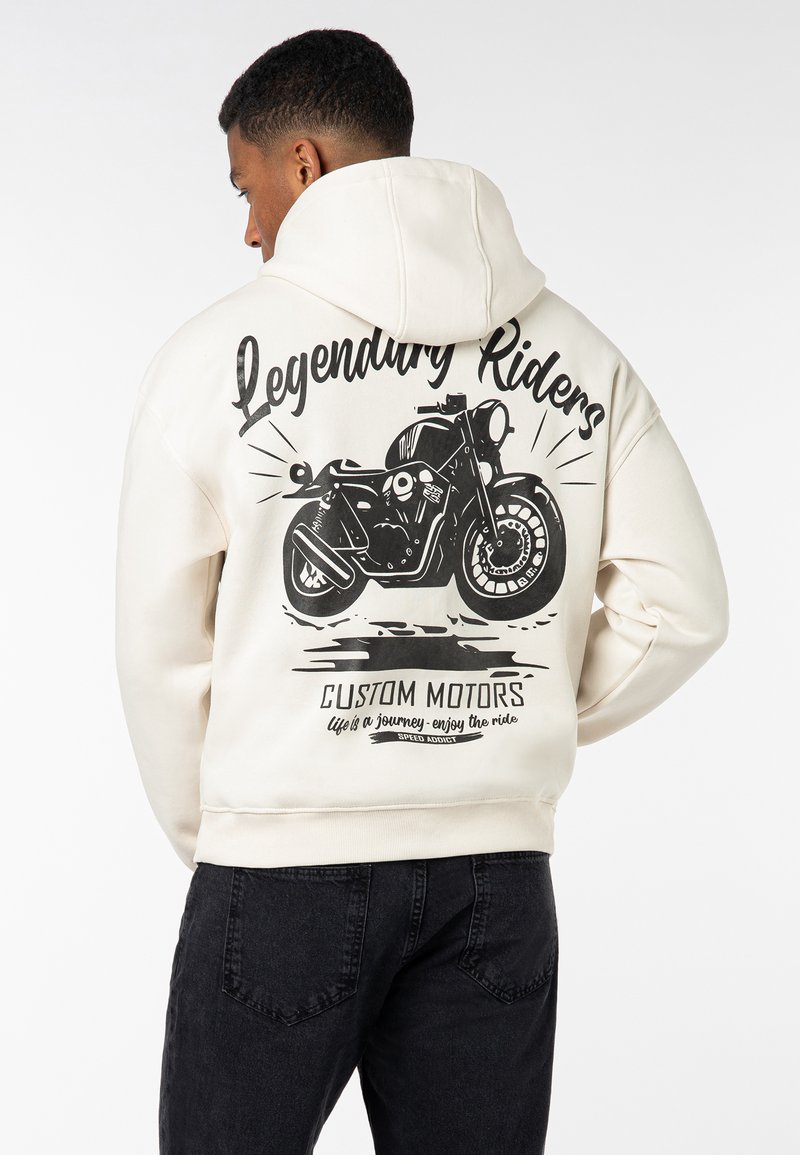 Hooded sweatshirt in cream with a black motorcycle graphic and text on the back. Features ribbed cuffs and hem, soft fabric texture.
