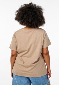 T-shirt beige à manches courtes en tissu doux avec une texture mouchetée. Coupe décontractée avec un col rond et un ourlet légèrement courbé.