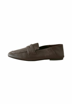 Bruine leren loafer met een puntige neus, decoratieve band en lage platte zool, getoond vanuit de zijkant tegen een witte achtergrond.