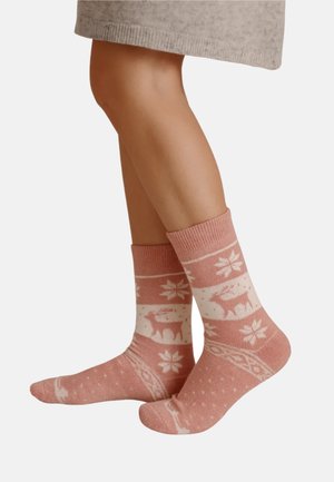 Gestrickte Socken in sanftem Rosa mit weißen Mustern, die Hirsche, Schneeflocken und Punkte zeigen. Knöchellange Ausführung mit gerippten Bündchen für Komfort.