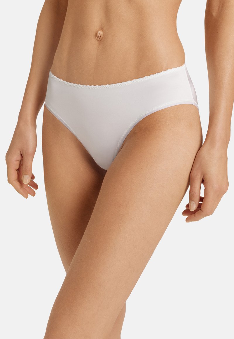 Vita mid-rise trosor gjorda av slät material, med scalloped spetsdekoration vid midjebandet och en klassisk snittdesign.