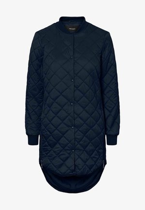 Tengerész kék steppelt dzseki kerek gallérral, patentgombokkal, hosszú ujjal és oldalsó cipzárakkal. Jellemzője a hosszabb hátsó szegély és az elasztikus mandzsetta.