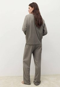 Conjunto de ropa de casa gris que incluye una camiseta de manga larga y pantalones de corte holgado. Tela suave con una textura lisa y un diseño minimalista.