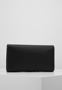 Mustasta, teksturoidusta materiaalista valmistettu suorakulmainen clutch-laukku, jossa on sileä viimeistely, minimalistinen muotoilu ilman näkyviä metalliosia tai korostuksia.