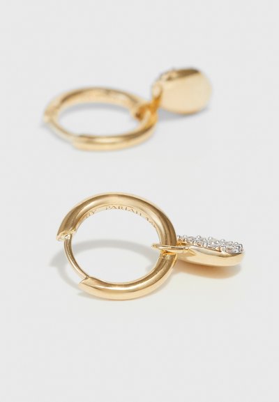 Χρυσά σκουλαρίκια κρίκοι με λεία, στρογγυλή φόρμα, διαθέτοντας ένα κρεμαστό κόσμημα διακοσμημένο με μικρές, διαφανείς πέτρες για πρόσθετη λεπτομέρεια.