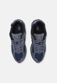Gray and navy athletic sneakers with mesh and suede materials, featuring a padded collar and textured sole. Laces and logo are visible.