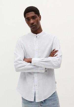 Cămașă button-up cu dungi albastre deschise, guler mandarin, nasturi galbeni și margine curbată. Are mâneci lungi și detalii subtile cu logo.