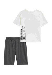 T-shirt blanche avec texte noir et logo sur le côté, assortie à un short gris foncé avec une taille élastique.