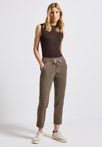 Donkerbruine mouwloze top gecombineerd met lichtbruine textuur joggers met een elastische tailleband, verstelbaar trekkoord en zijzakken.