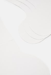 Des feuilles de papier blanches aux bords arrondis disposées en couches superposées, mettant en avant une texture lisse et un éclat subtil sur un fond clair.