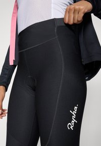 Hoogwaardige zwarte fietsshorts met een padding, contrasterende stiksels en een wit logo op het been voor zichtbaarheid.