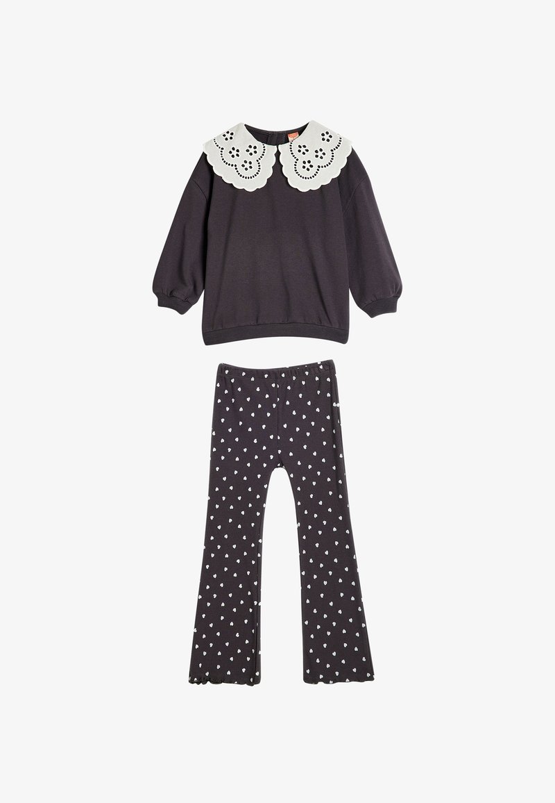 Maglione grigio scuro con colletto bianco a scallop e dettagli a occhio, abbinato a pantaloni grigi scuri a campana con un motivo a cuori bianchi.