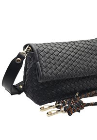 Sac à main en cuir tissé noir avec une forme structurée, doté d'un rabat supérieur, de ferrures dorées et de sangles à double texture avec des accents orange.