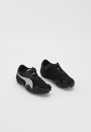 Scarpe sportive nere con suole testurizzate, una silhouette snella e un design con accenti grigi; presentano una cinghia di chiusura sicura e un sistema di allacciatura.