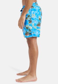 Modré plavecké šortky s tropickým vzorom, na ktorom sú palmy a špirálový text. Materiál je ľahký, so zvýšeným pásom a šnúrkou na stiahnutie.