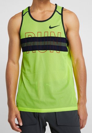 Mężczyzna ubrany w jasną zieloną siateczkową, bezrękawnik do biegania z czarnymi paskami i napisem "RUN", w zestawie z ciemnymi szortami.