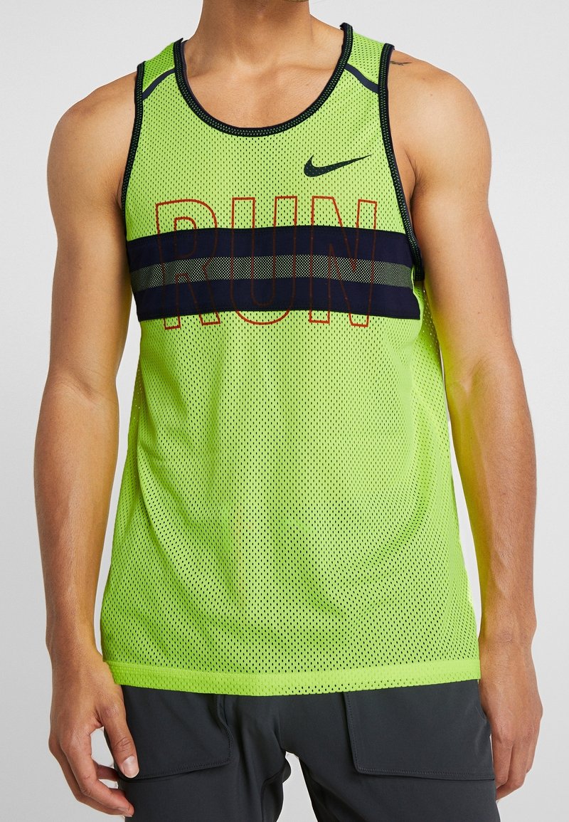 Homme portant un débardeur de course en maille vert vif à rayures noires avec le texte "RUN", assorti à un short foncé.