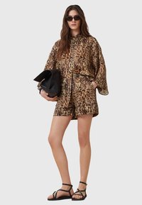 Leopard print kimono-style top with matching shorts, made of lightweight fabric. Accessories include a black bag and strappy sandals.