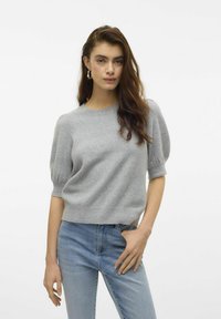 Szary, dzianinowy sweter z krótkimi, bufiastymi rękawami i okrągłym dekoltem. W połączeniu z jasnoniebieskimi dżinsami. Miękka faktura i luźny krój.