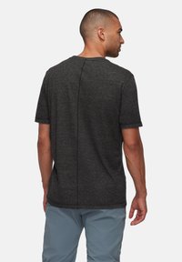 Korte mouwen, donkergrijs t-shirt met een ronde hals, gestructureerde stof en een middennaad detail aan de achterkant. Draagt met lichtblauwe broek.