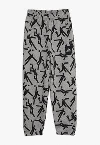 Szare dresy z czarnym abstrakcyjnym wzorem, elastycznym paskiem w talii, bocznymi kieszeniami oraz małą naszywką z czarnym logo Adidas.